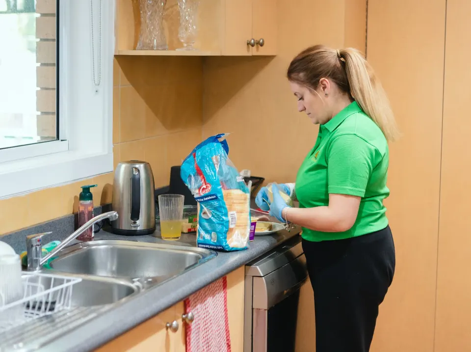 A Help on Wheels support worker preparing a light meal in a participant's kitchen