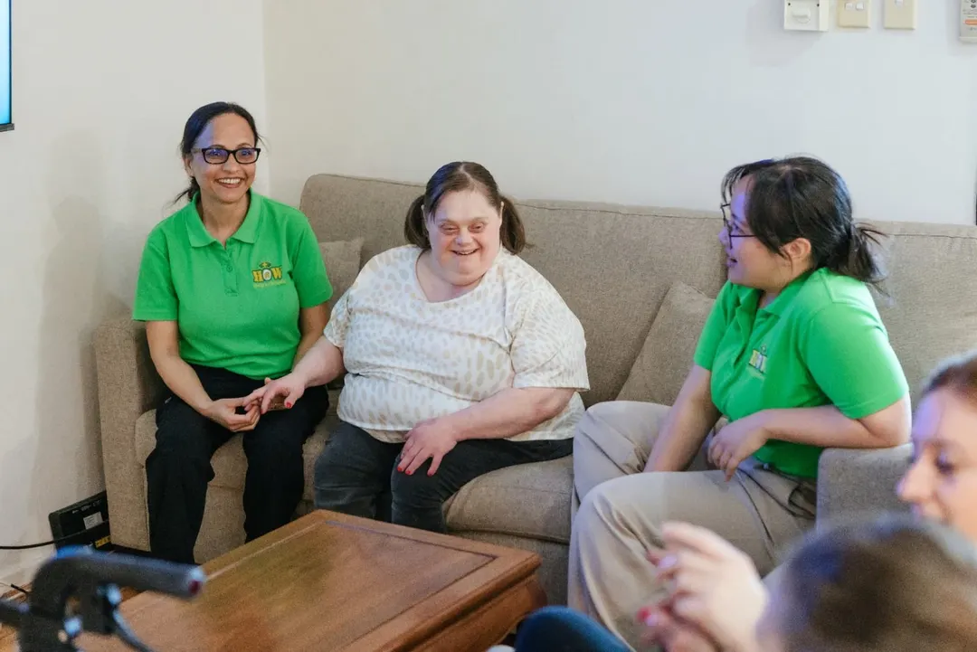 Help on Wheels support workers chatting and laughing with a participant on a couch