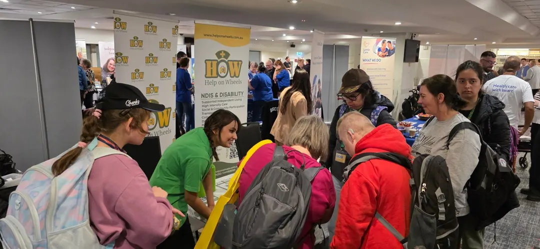 Visitors at the Help on Wheels stand at a community expo